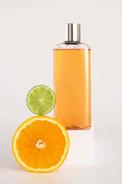 Shampoo or shower gel mockup on a square podium, orange and lime lie nearby
