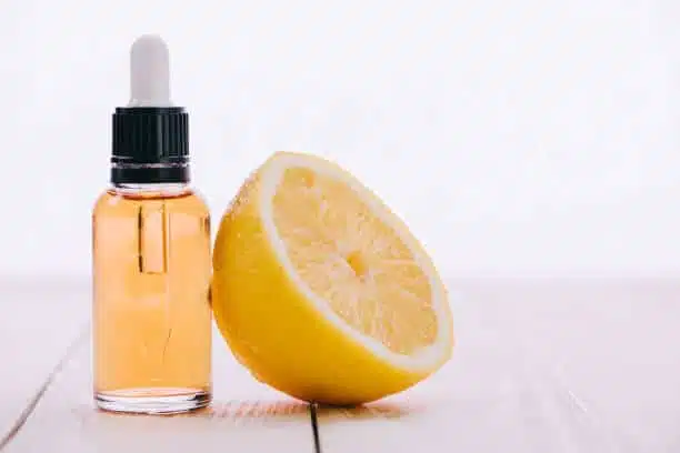 cbd oil in bottle with dropper and half of lemon on wooden surface isolated on white