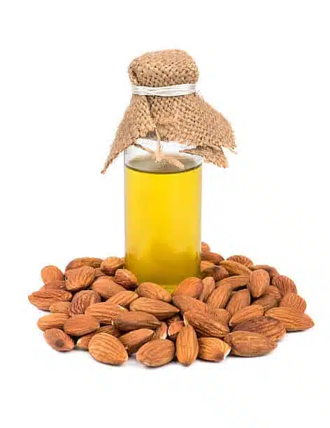 Bottle of almond oil with nuts on a white background
