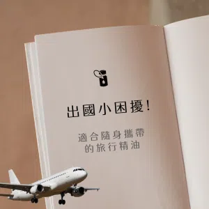 畫面呈現奶色系精裝書本空白頁，上方一個黑色精油瓶圖示，中間文字「出國小困擾！適合隨身攜帶的旅行精油」，左下角加入飛機圖像，背景為溫暖窗光灑落在亞麻布上的柔和光影，整體營造出精油與旅遊結合的氛圍。