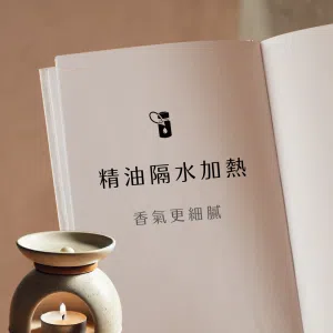 這張圖展示奶色系波西米亞風格的隔水加熱精油香薰場景：一盞陶瓷香薰爐前擺開書頁，底部蠟燭緩緩燃燒，頂部水盤中浸著精油，柔和窗光斜射，整體氛圍寧靜而細膩。
