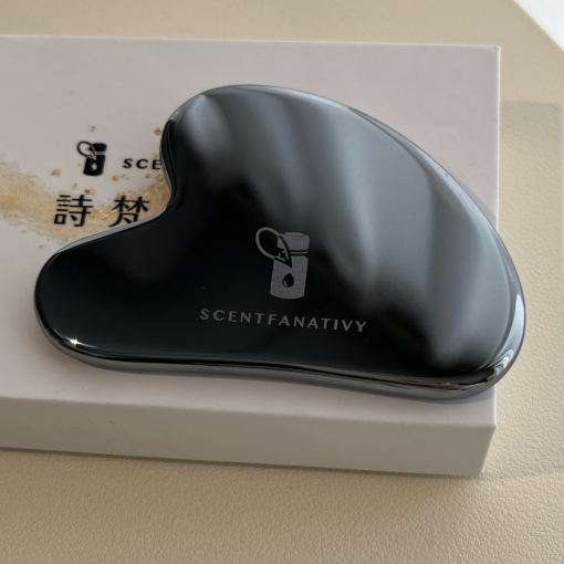SCENTFANATIVY 黑色太赫茲刮痧板，放置於品牌禮盒之上，展現低調奢華感。太赫茲石材質堅硬耐用，具有能量與美觀兼具的特性，適合臉部按摩、肩頸刮痧，促進循環與放鬆。